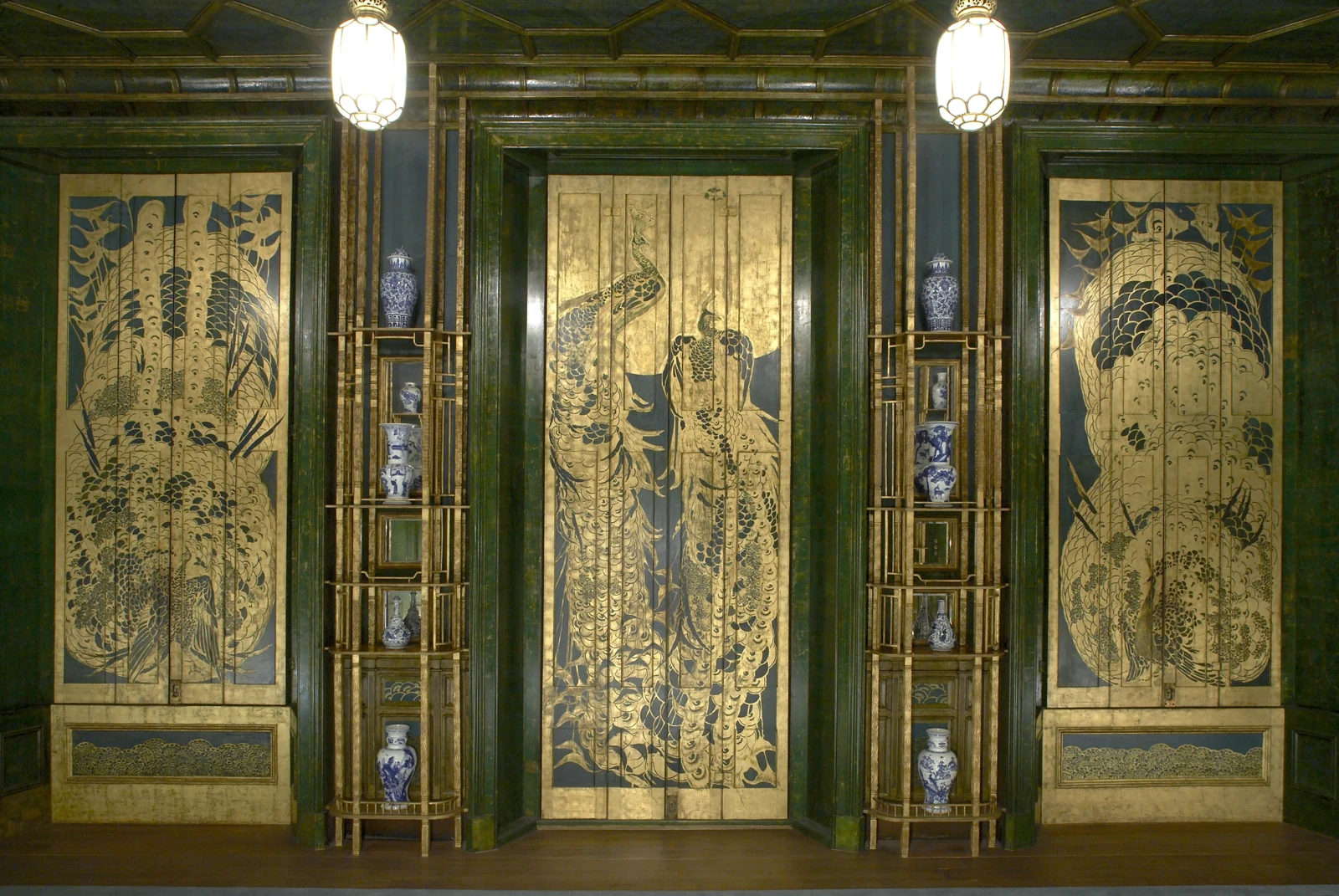 A richly decorated interior of the Peacock Room, with shelves of ceramics and a peacock motif.